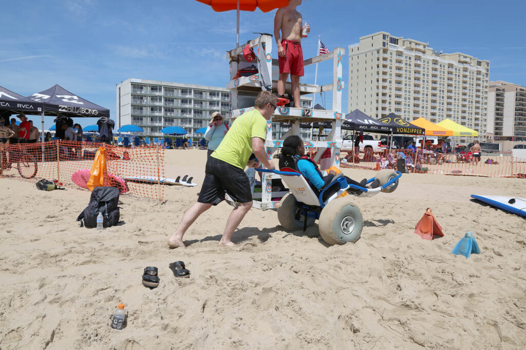 Sand Rider beach wheelchair being pushed on two wheels at the beach