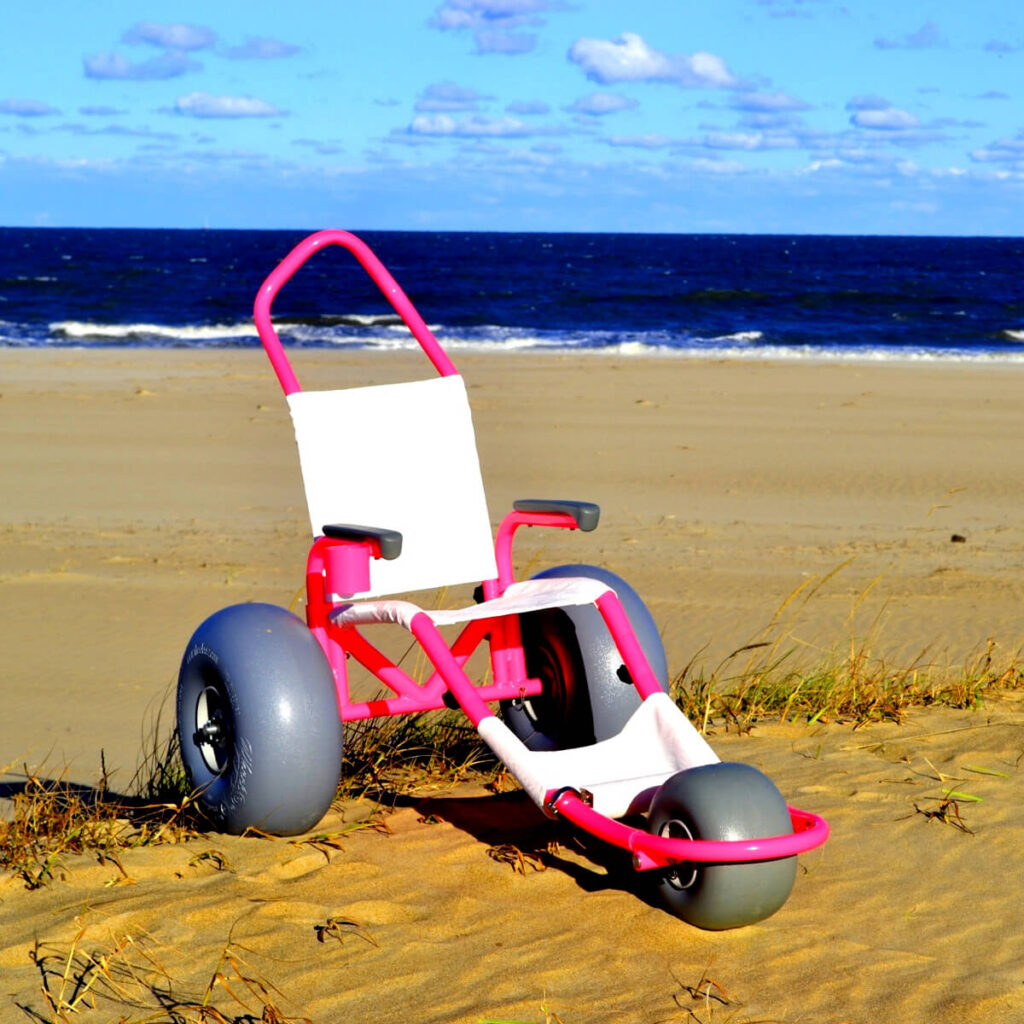 Pink Sand Rider beach wheelchair pictured on the sand